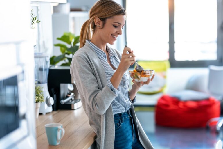Woman eating from bowl in kitchen