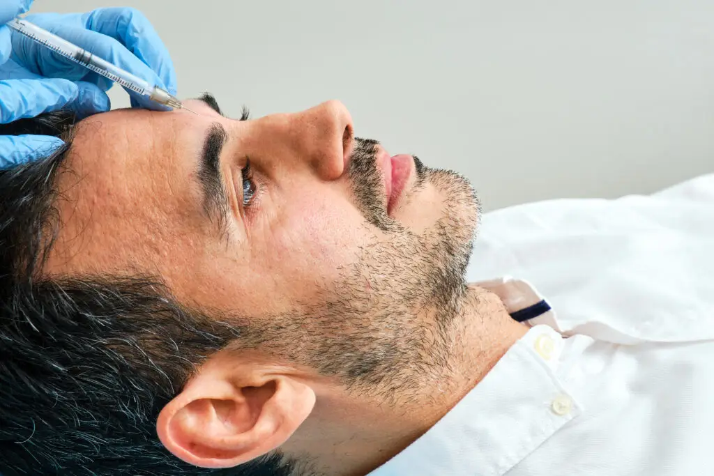 45-year-old dark-haired man in an aesthetic clinic being treated with botulinum toxin in a miami beach medical spa