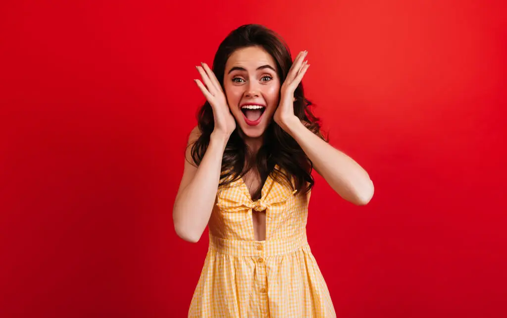 emotional woman happily shouts red wall curly lady yellow checkered outfit posing 1