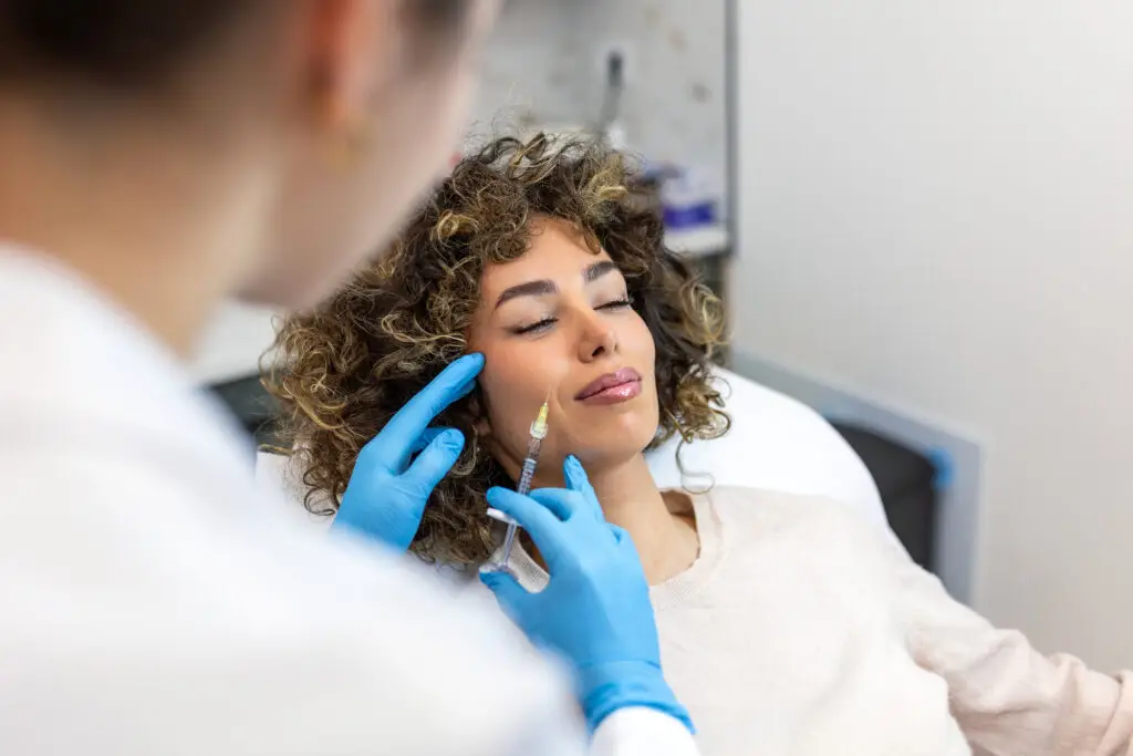 Close up of professional surgeon injecting botox in woman's cheek. Facial rejuvenation, dermal filler treatment concept. Female doctor in gloves performing aesthetic procedure in a miami beach medical clinic.